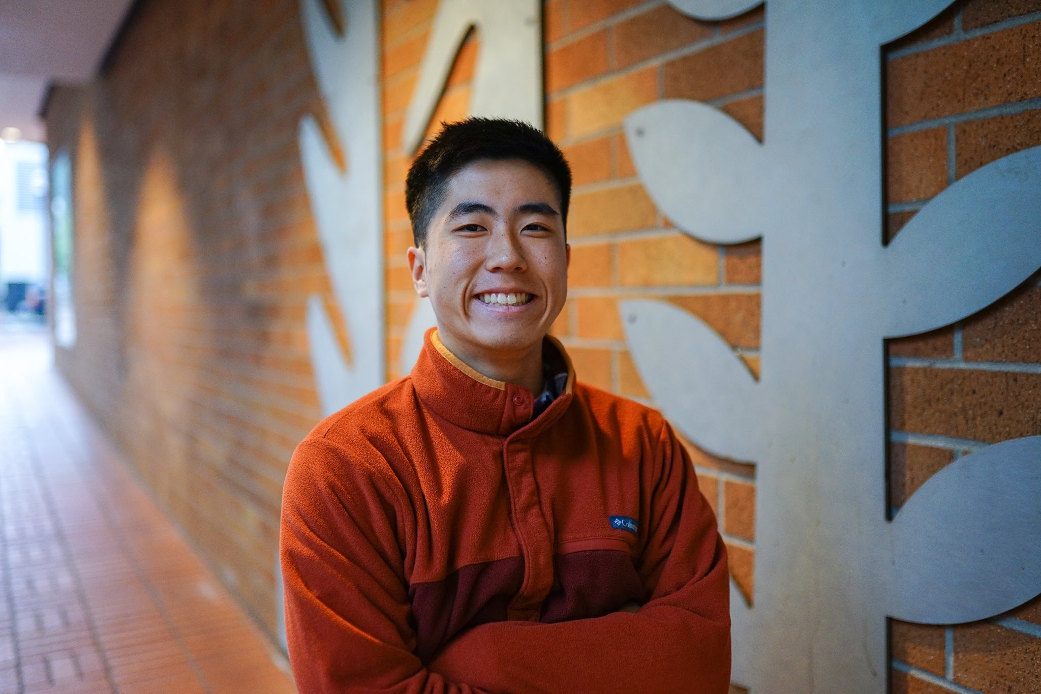 Chris smiling infront of a brick wall